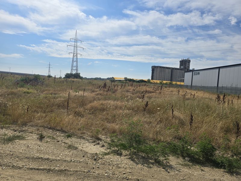 Wide view of the undeveloped land with high-voltage pylons, factory and hall